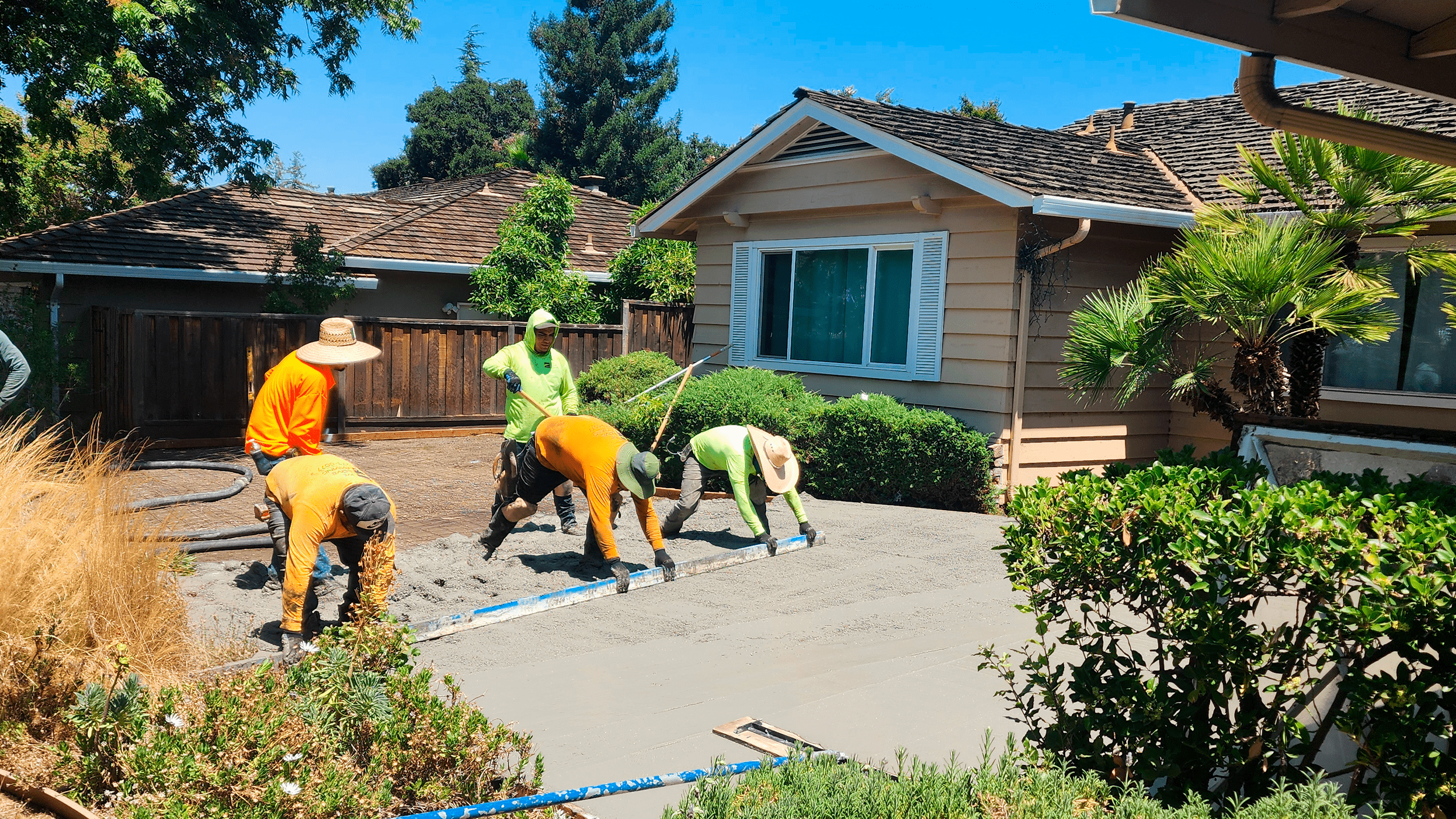 spreading and leveling fresh concrete on a driveway in a residential area