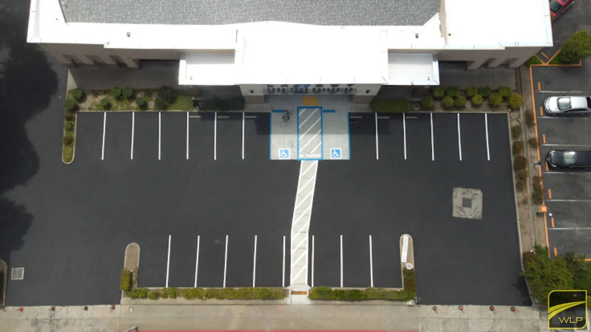 Home 4 Overhead view of a black asphalt lot with fresh white stalls and blue ADA handicap spaces. Project by We Love Paving in Northern California, CA.