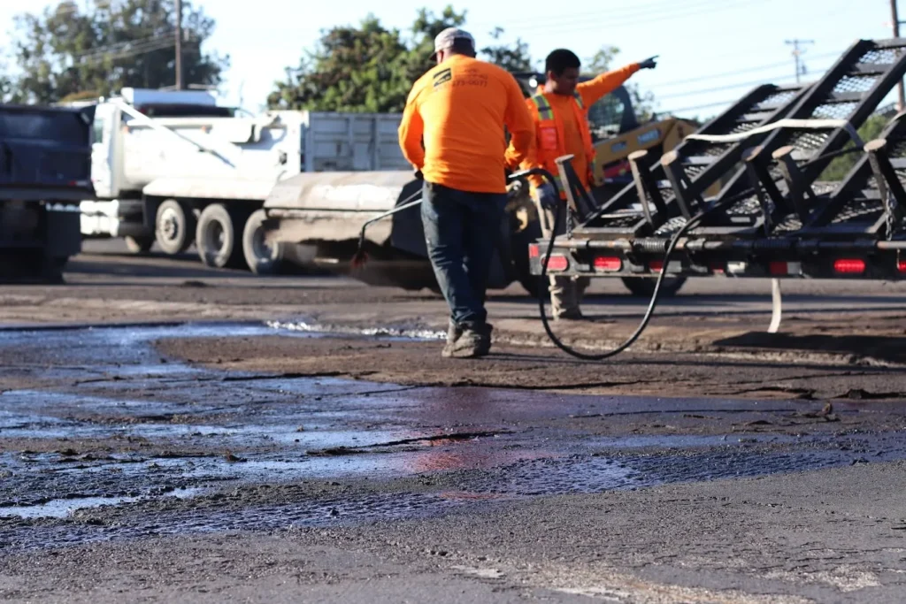 Sealcoating 1 Workers applying a black sealcoat to a cracked asphalt surface during a repair project in Novato. Project by We Love Paving in Novato, CA.