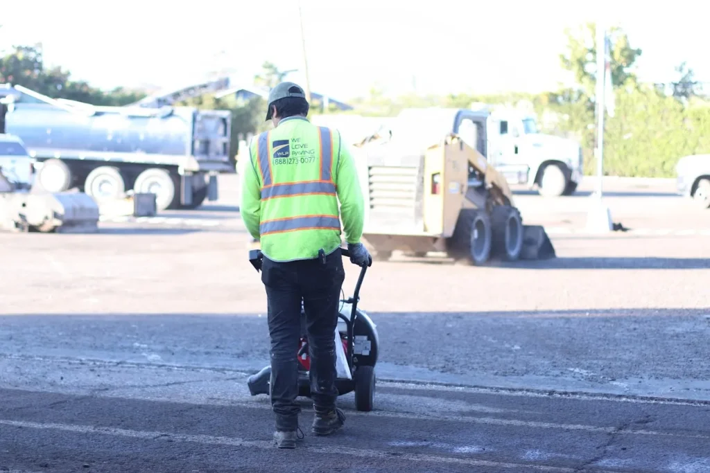 Distribution Center Paving 1 A worker in a safety vest using a power blower to clean a parking lot surface in San Rafael. Project by We Love Paving in San Rafael, CA.