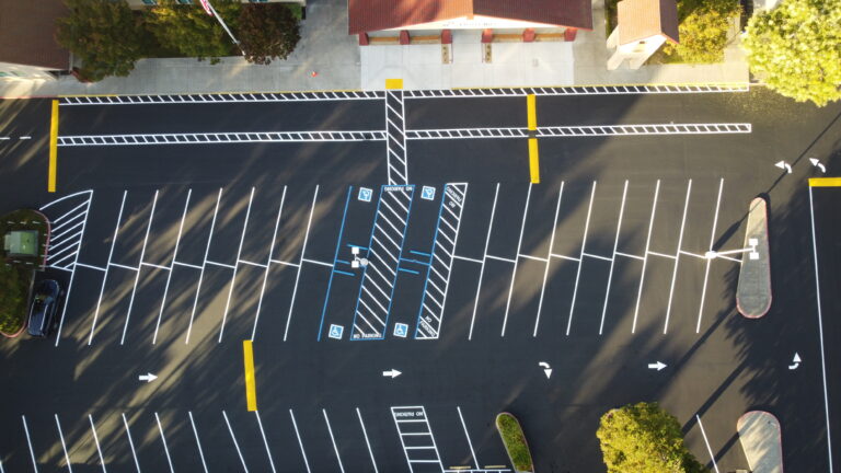 Top-down view of a large, freshly paved parking lot in Santa Clara with new white and yellow line striping. Project by We Love Paving in Santa Clara, CA.