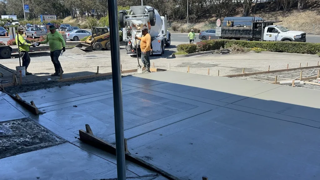 Apartment Complex Parking Lot Paving 4 Workers and a concrete mixer truck pouring fresh cement for a new parking lot surface in Sausalito. Project by We Love Paving in Sausalito, CA.