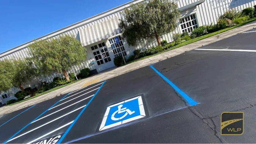 Showroom Exterior Paving 2 Handicap parking space with blue accessibility symbol and painted access aisle in a new asphalt lot. Project by We Love Paving in Northern California, CA.