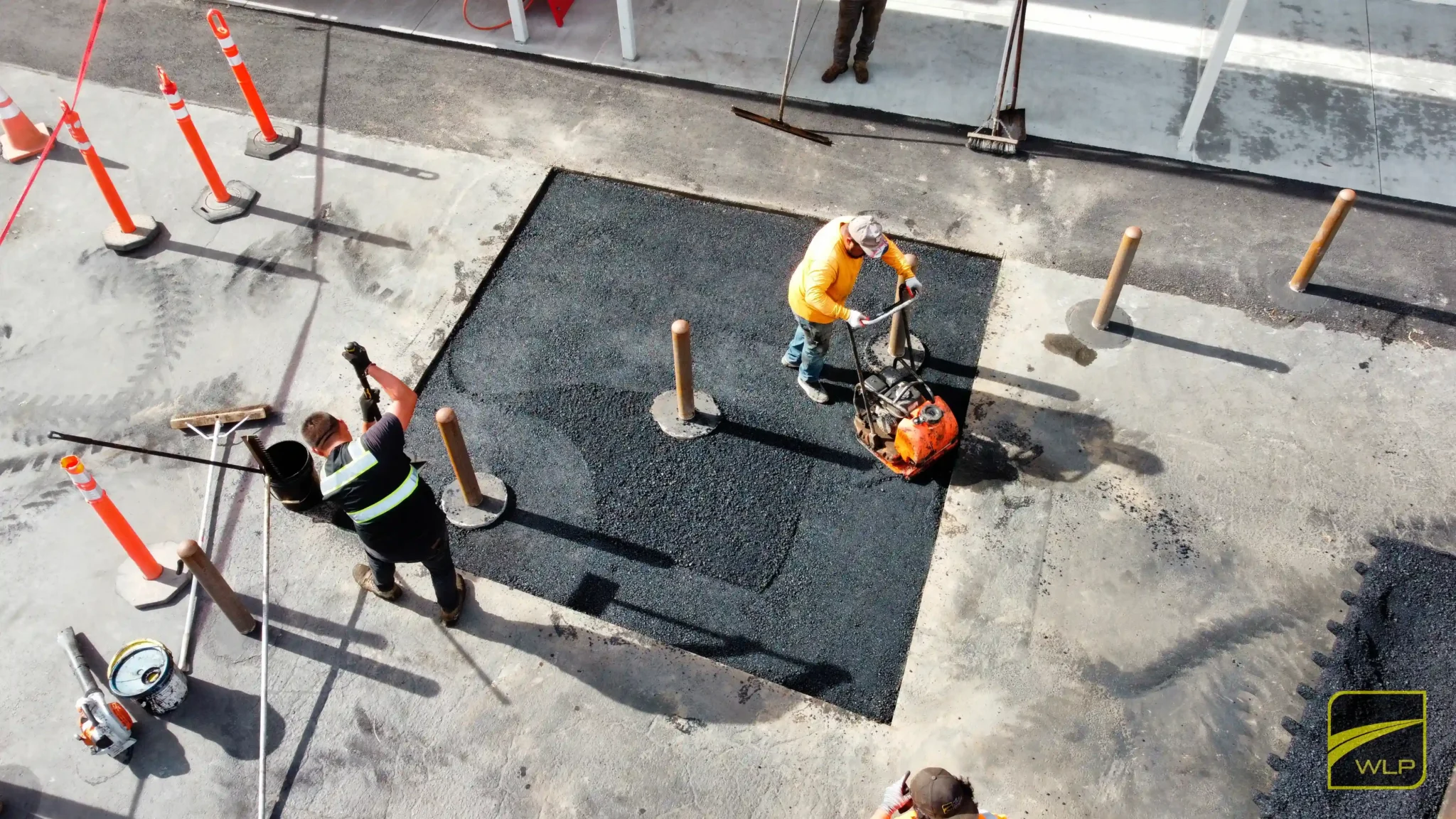 Projects 1 We Love Paving crew performing asphalt patching and compaction using a vibratory plate compactor to ensure a smooth and durable surface in a commercial area. Project by We Love Paving in Northern California, CA.