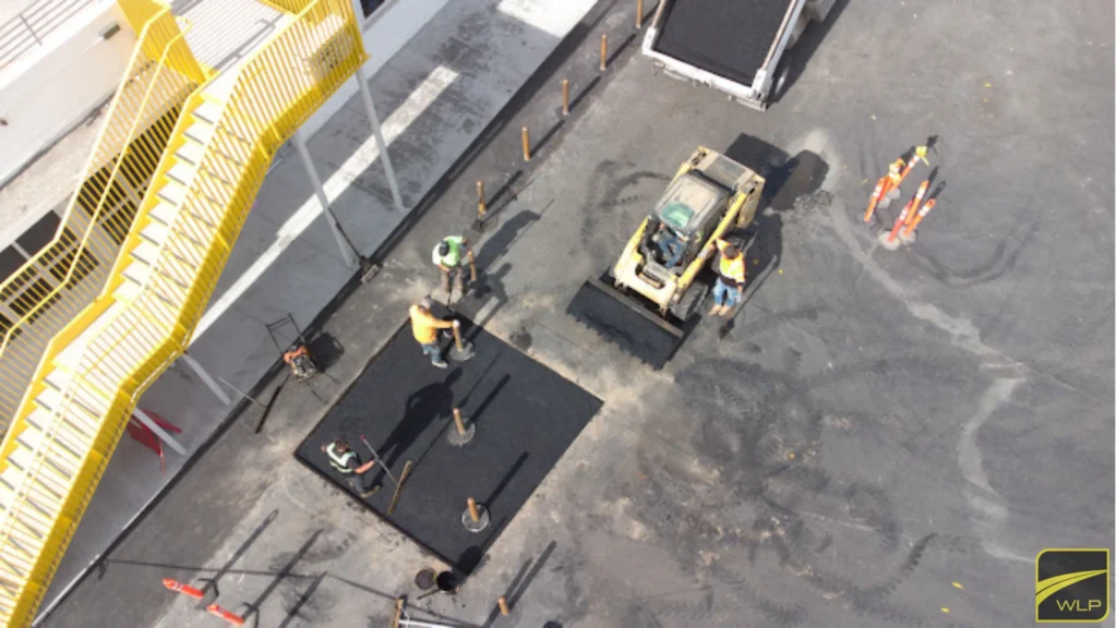 Hospital Parking Lot Paving Service 3 Aerial perspective of workers performing asphalt patching near outdoor stairs.