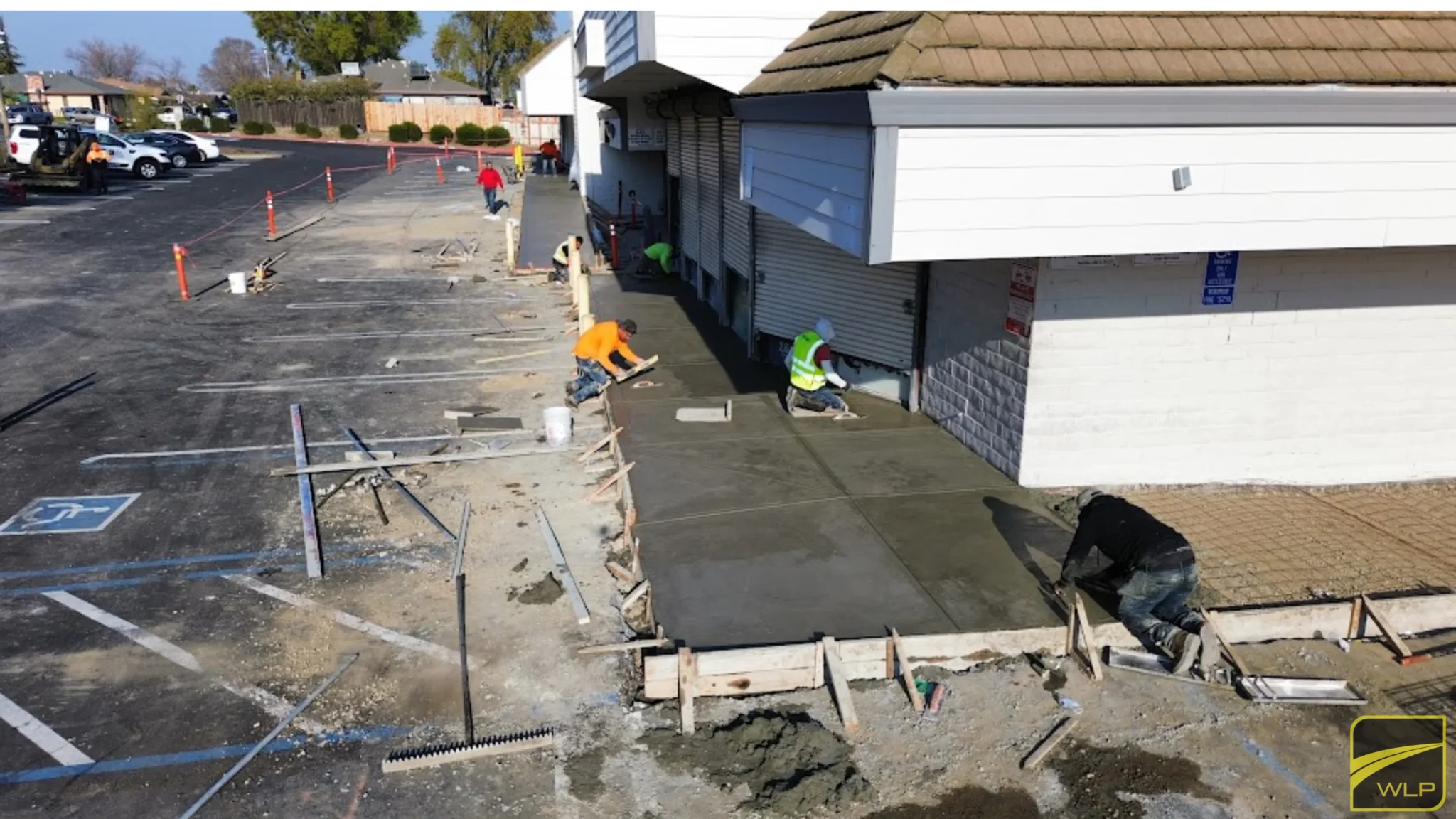 Project Gallery 7 Construction crew pouring and smoothing wet concrete for a new commercial sidewalk.