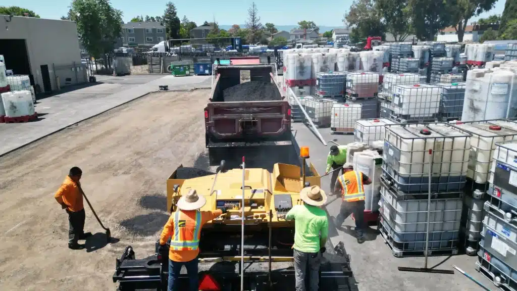 Unveiling the Reigning Champion: The Most Durable Paving Solutions 2 Aerial view of an asphalt paver and crew working in an industrial yard.