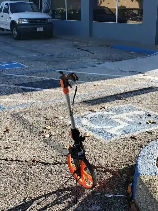 Measuring wheel on a parking lot next to an accessible stall